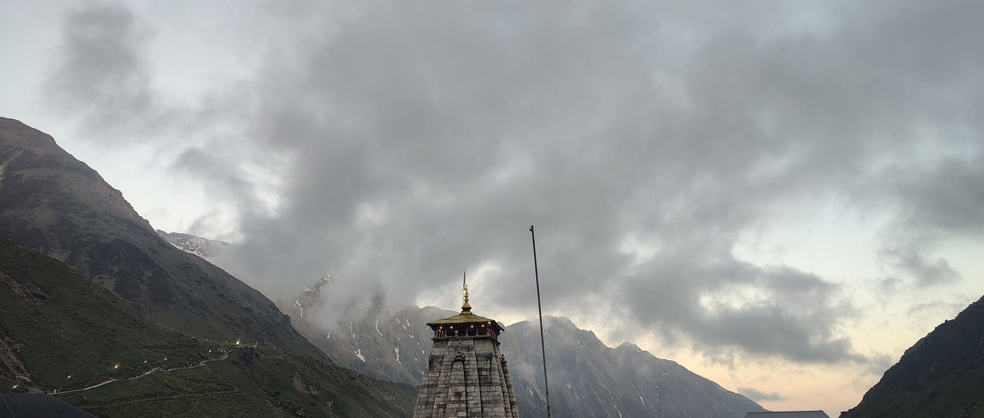 Kedarnath Temple beneath cloud-wrapped Himalayan peaks at dusk